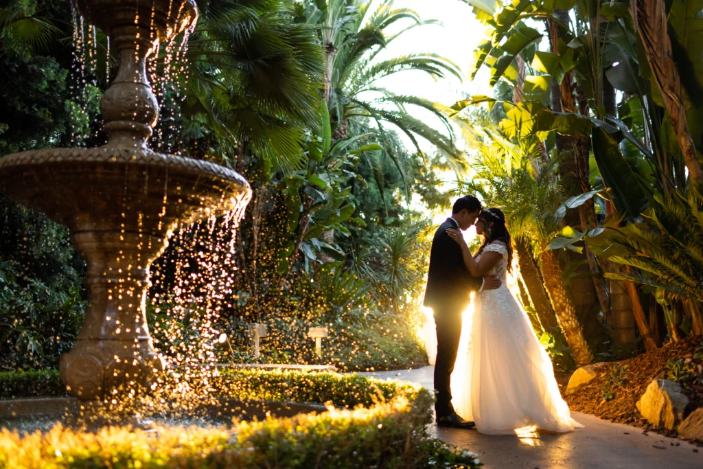 Newlyweds kissing by a lighted fountain at night by GC Event Studio