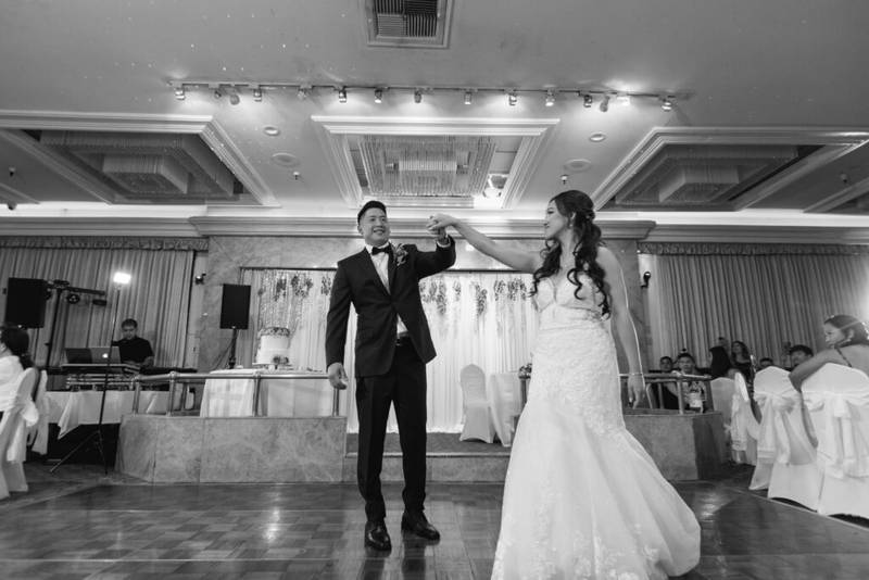 Bride and groom dancing in a decorated ballroom.