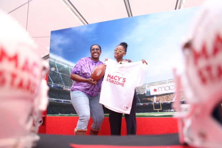 Guests posing for a fun photo in front of a stadium-themed backdrop at a photo booth activation.