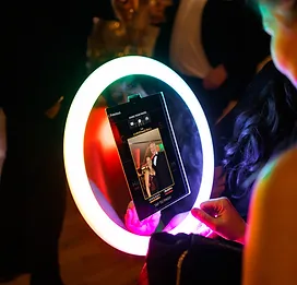 Close-up of a handheld photo booth device at a lively event.