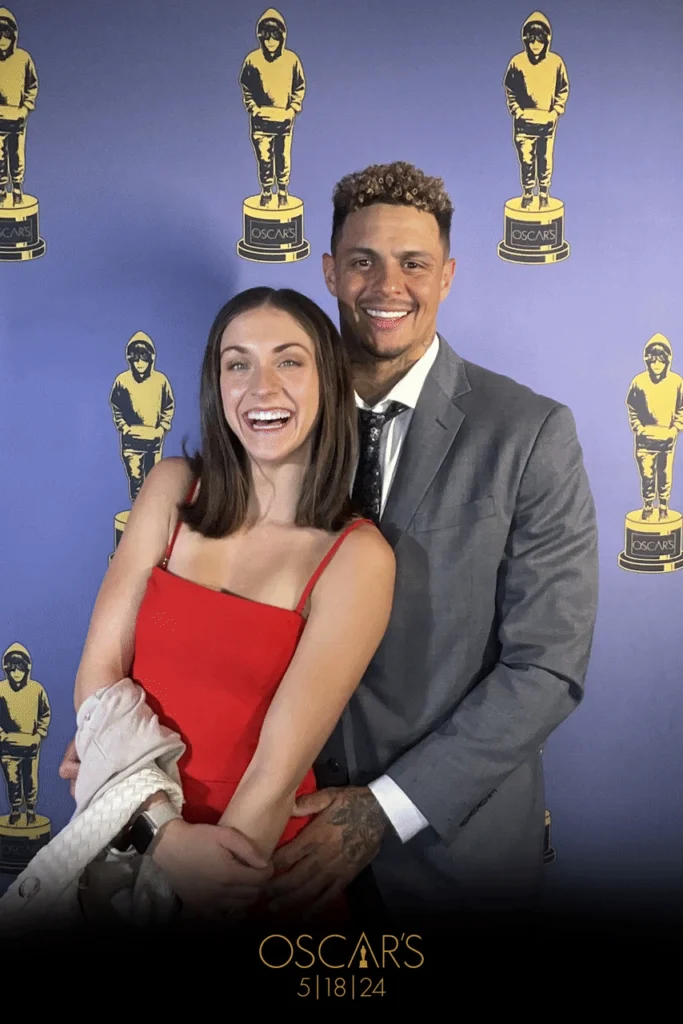 Couple posing in front of Oscars-themed backdrop at event photo booth.