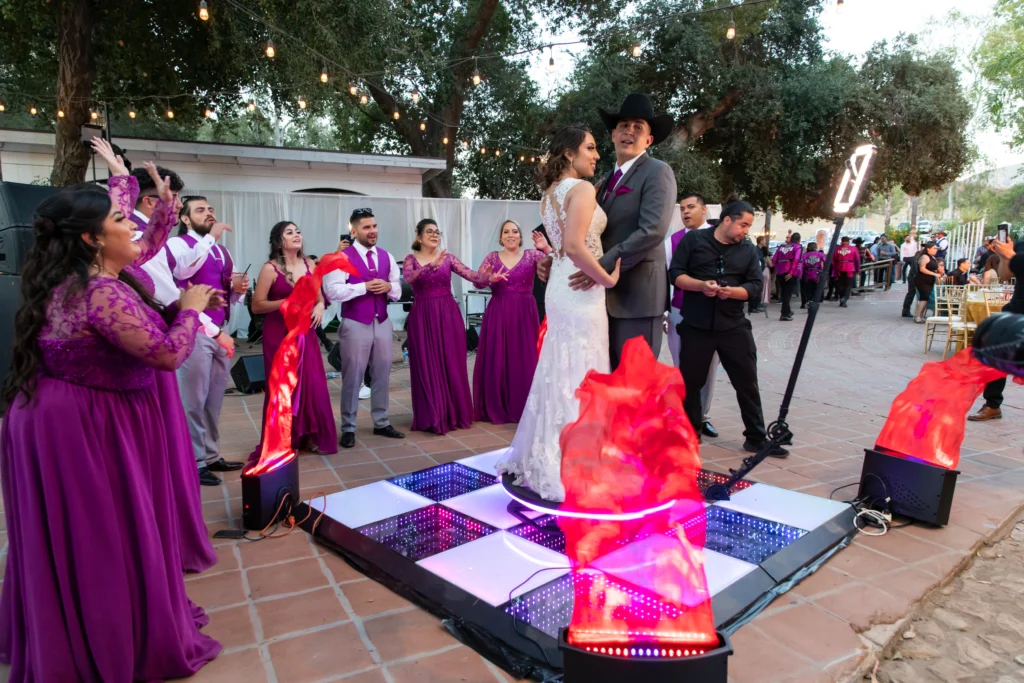 Bride and groom with guests on a 360 photo booth at a vibrant wedding celebration.