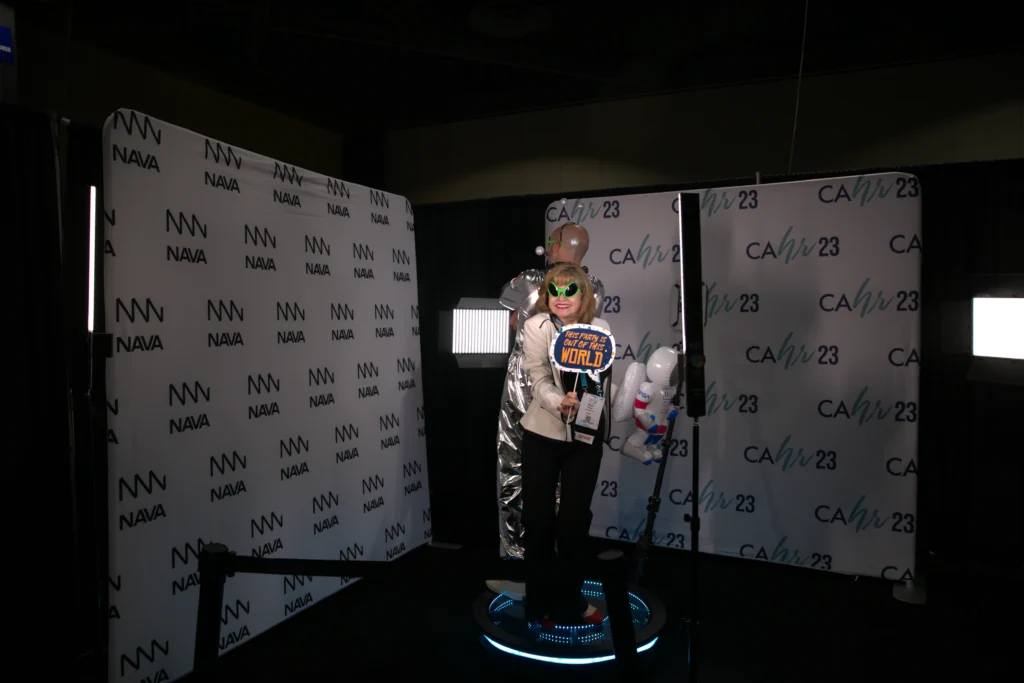 Woman posing with fun props on a branded 360 photo booth at a convention.