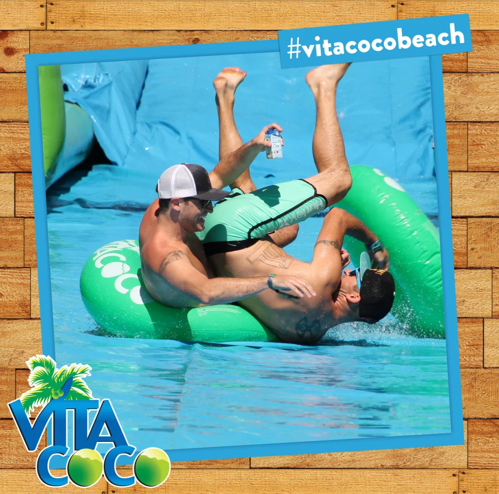 Two men having fun on a water slide at a summer-themed photo booth.