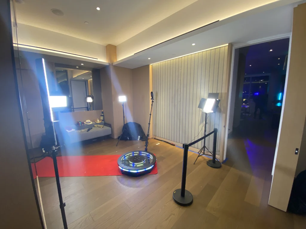 360 photo booth set up in a spacious hotel room with elegant lighting.