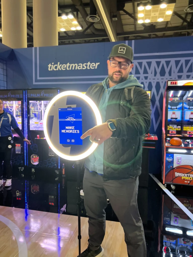 Man showcasing a mobile photo booth ring light at a trade show.