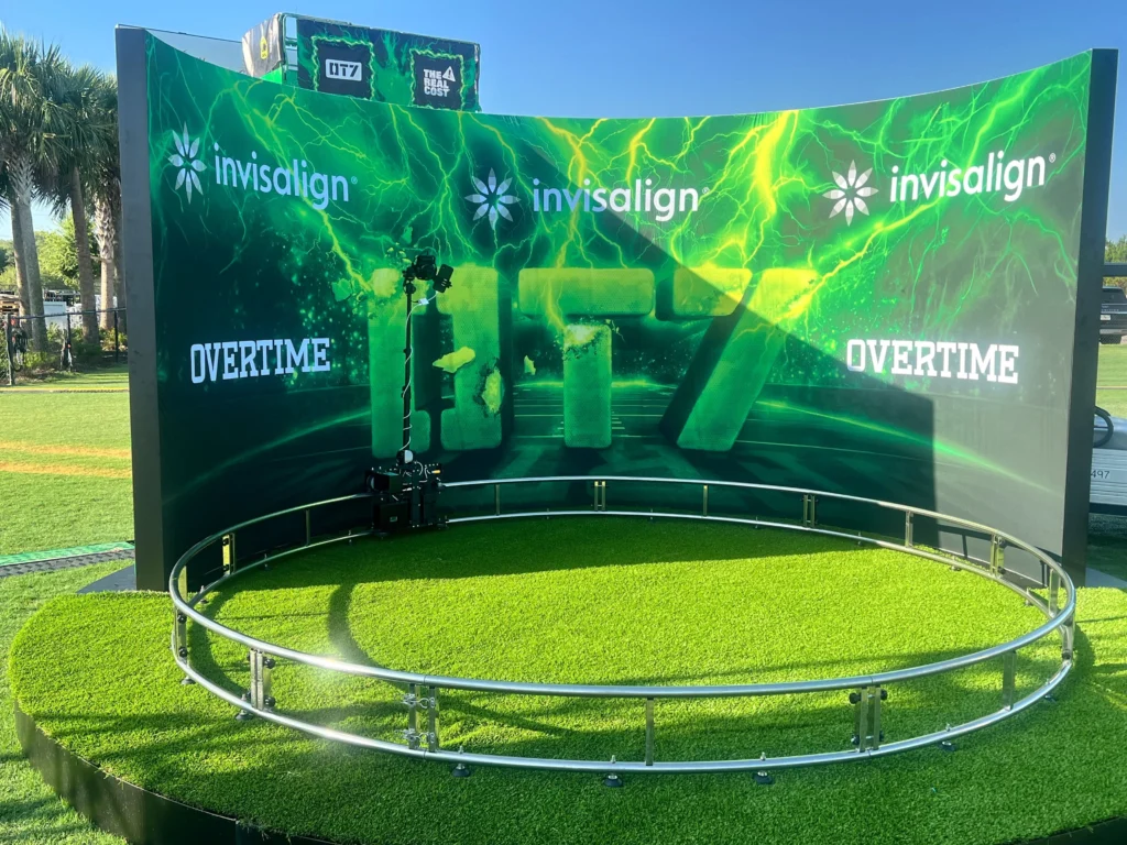 Green-themed 360 event photo booth at an outdoor promotional event with dynamic lighting.