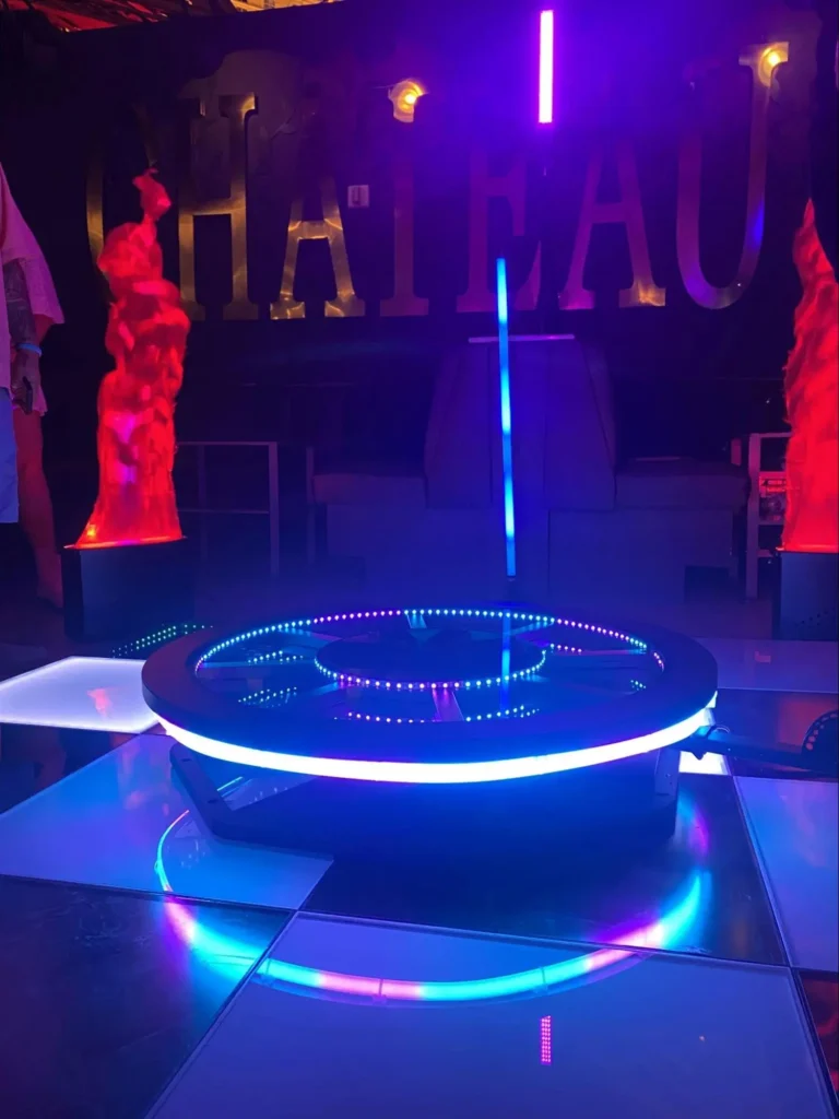 360 photo booth platform lit with neon colors at a nightclub, featuring dynamic red flame effects.