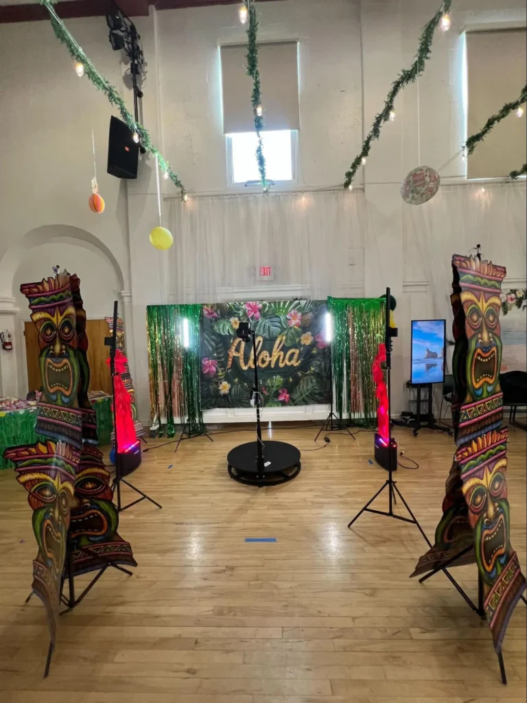 360 photo booth setup with tropical theme backdrop at indoor event venue.