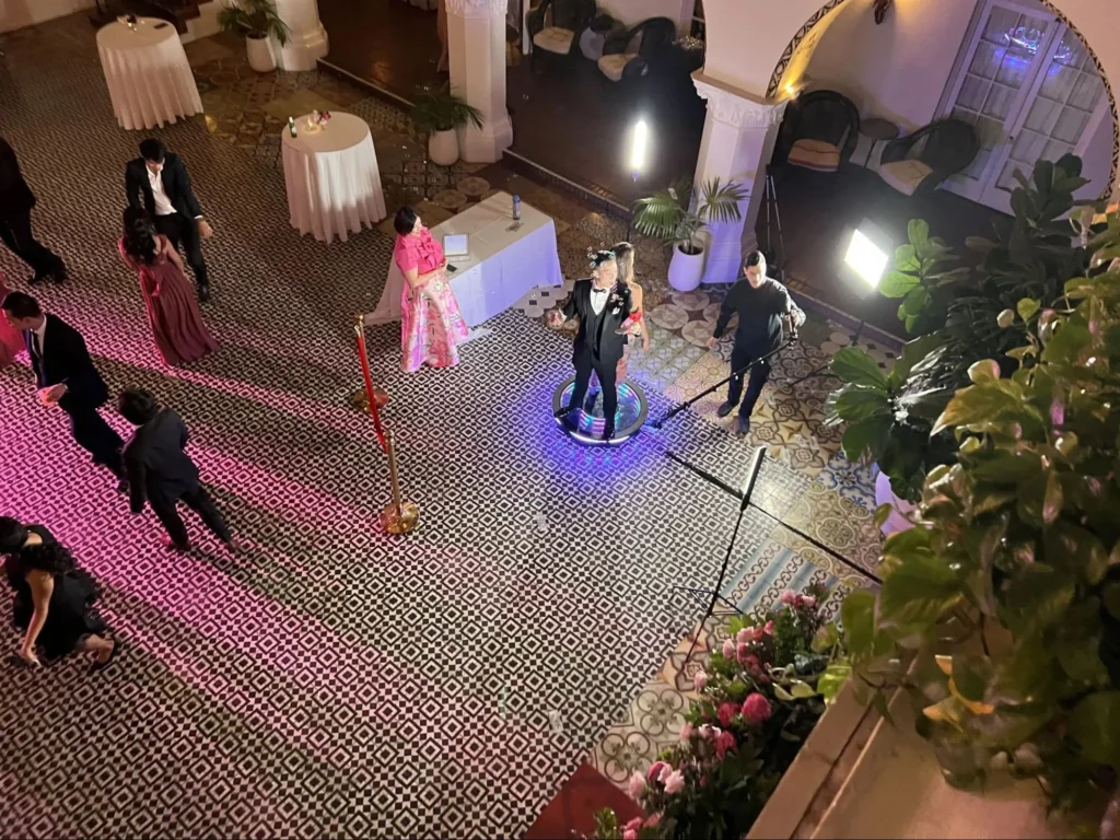 Aerial view of guests dancing on 360 photo booth platform at formal event.