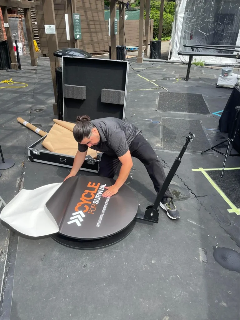 Technician setting up 360 photo booth platform outdoors.