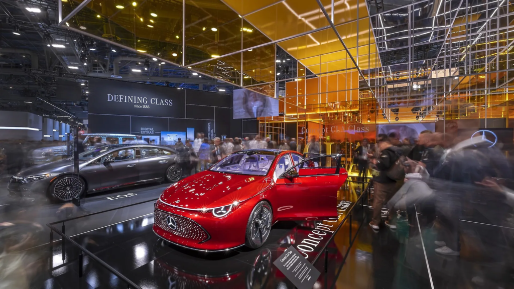 Busy car show scene with a futuristic red car display at a corporate event.