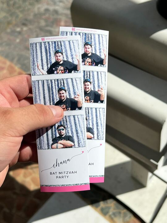 Hand holding a photo strip from a Bat Mitzvah with various poses of a man smiling and gesturing.