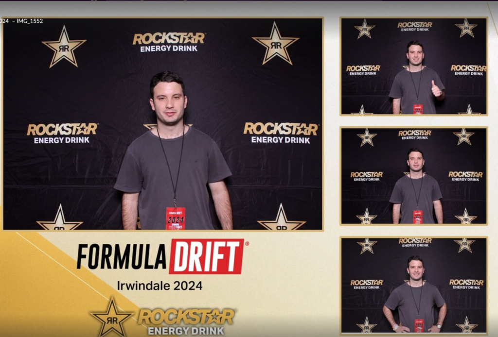 Man posing in a Rockstar Energy Drink branded photo booth at Formula Drift event.