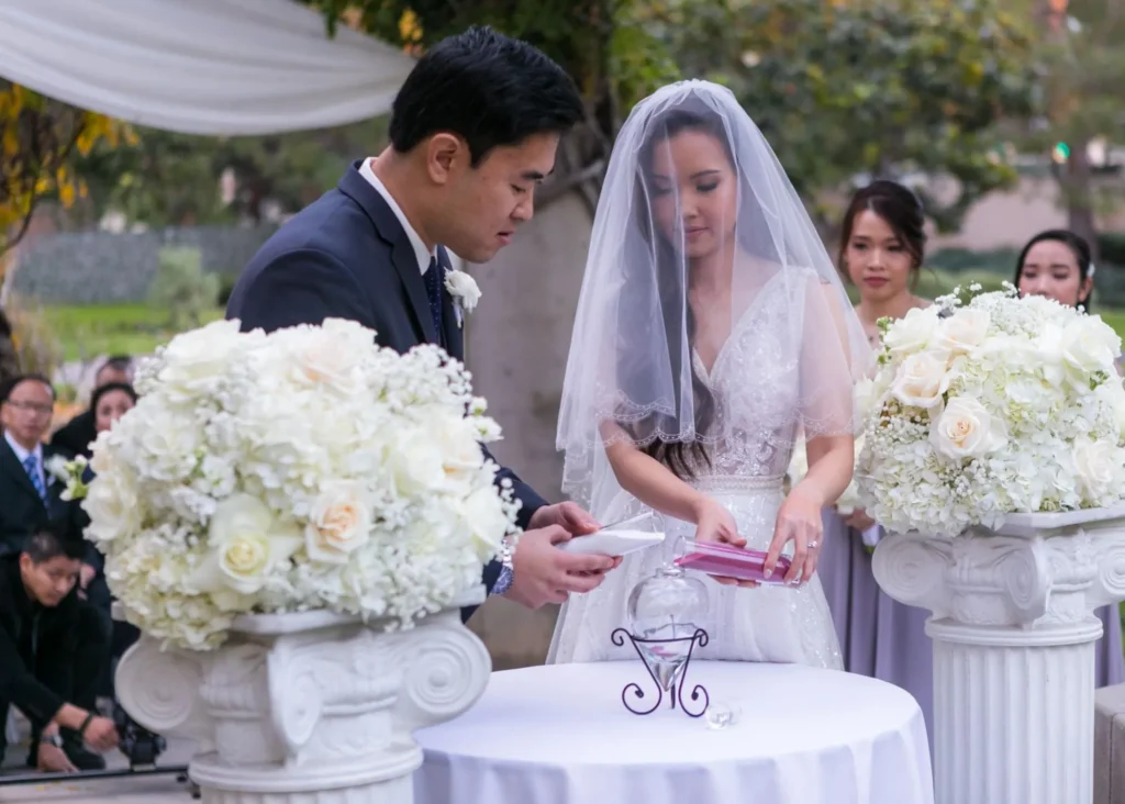 Bride and groom exchanging vows under floral arch.