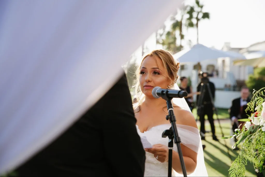 Bride delivering vows at outdoor wedding ceremony.