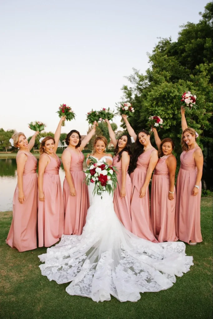 Bride with bridesmaids in blush dresses holding bouquets.