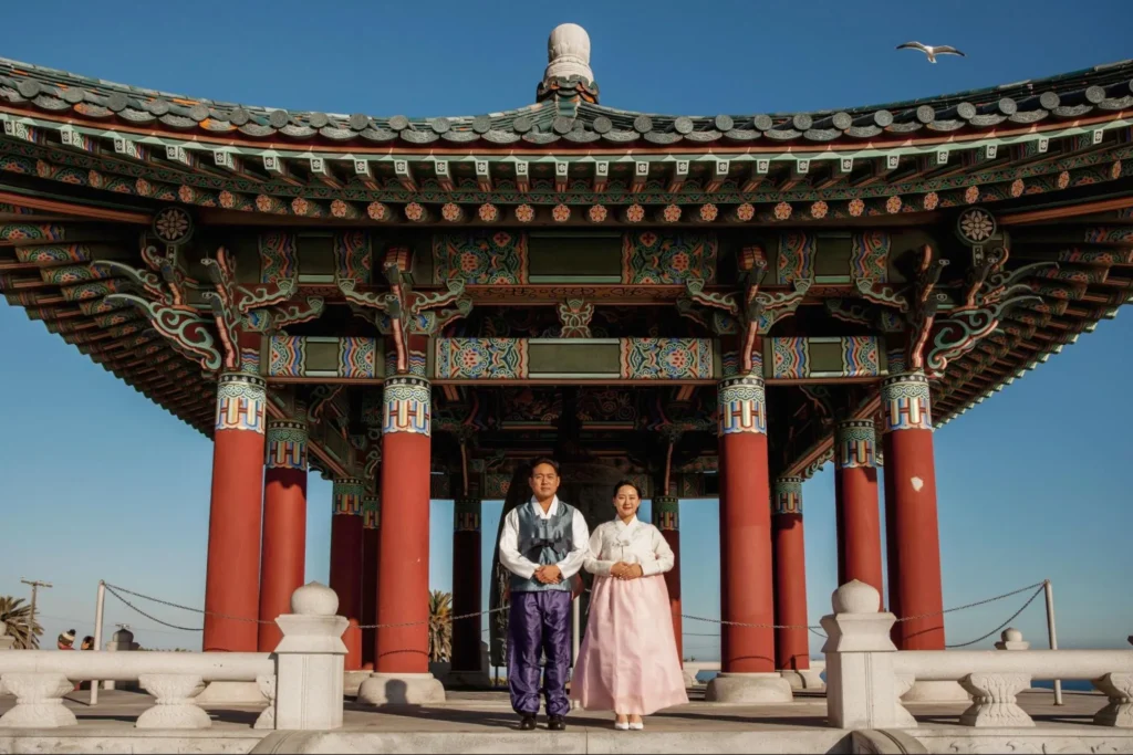 Couple in traditional Korean attire at colorful pavilion.