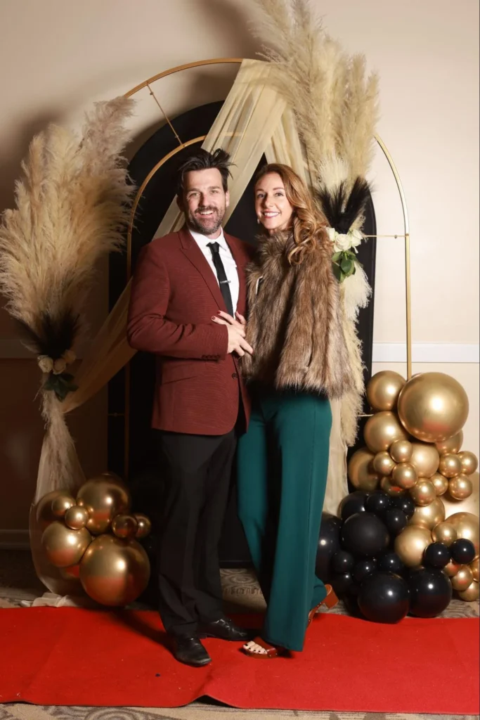 Couple posing with modern balloon decor at wedding photo booth.