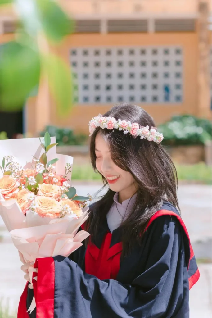 Creative graduation photo idea featuring a graduate with a floral crown and bouquet in natural light.