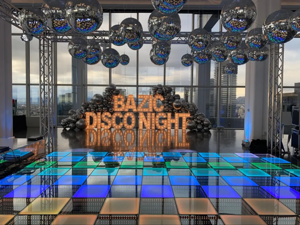 Disco-themed event setup with Bazic signage and reflective decorations.