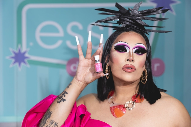 Drag performer showcasing pink nail polish at Essie brand activation event.