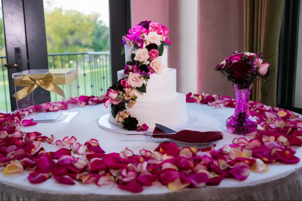 Elegant wedding cake surrounded by pink rose petals.