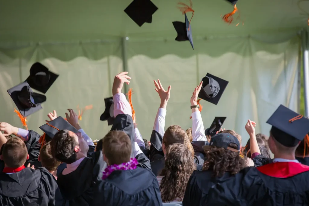 Graduating students throwing off their hats at graduation party.