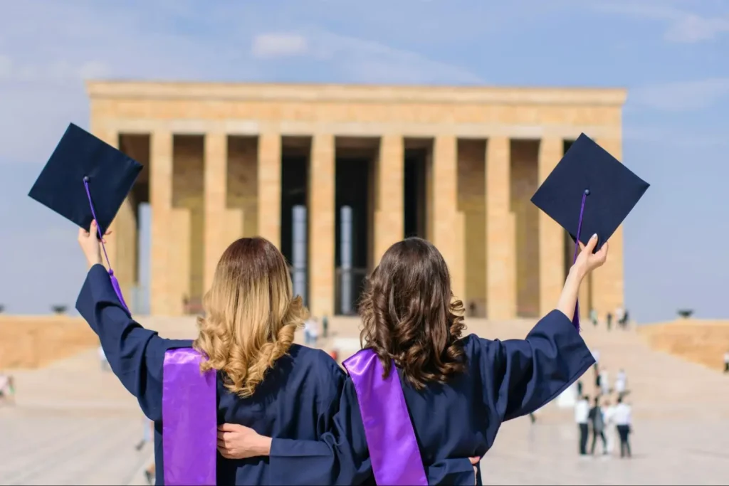 Graduation photo idea with friends showcasing caps in the air near a historical monument.