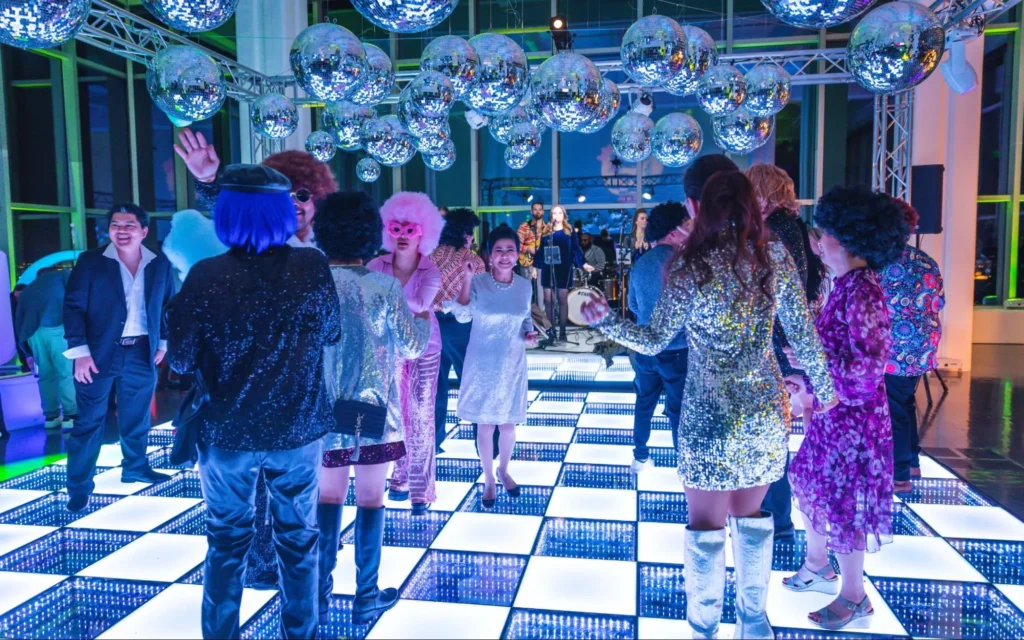 Guests dancing at a wedding with retro disco theme.