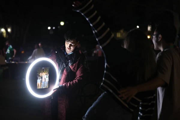 Interactive Roamer Booth capturing candid moments at an outdoor evening event with a vibrant display screen and ring light for on-the-go photo sharing. Perfect for dynamic event experiences.