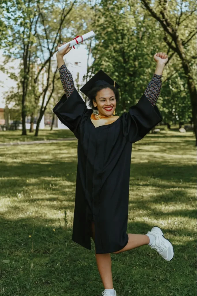 Joyful graduate celebrating outdoors with diploma in hand, showcasing a fun graduation photo shoot idea.