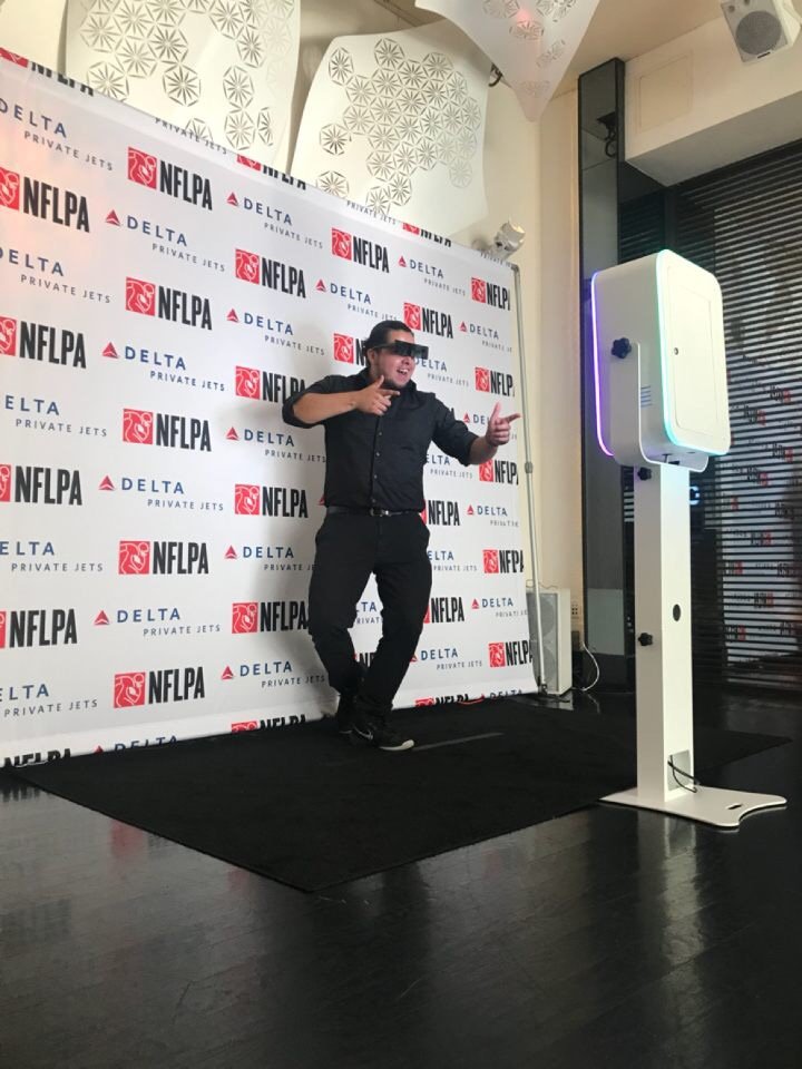 Man posing at a professional photo booth setup with branded NFLPA and Delta backdrop.