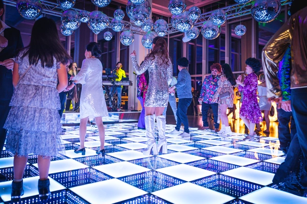 Guests dancing on a glowing LED wedding dance floor under sparkling disco balls, creating an unforgettable celebration atmosphere.