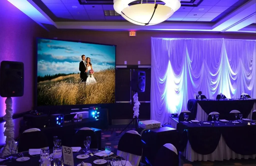 Romantic wedding venue with draped walls and large projector.