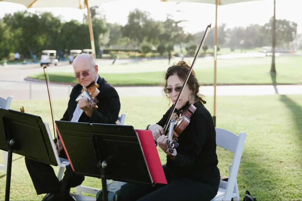 String musicians performing during an outdoor wedding ceremony.