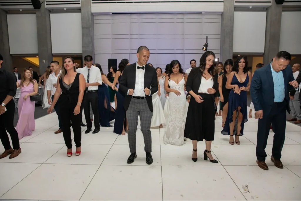 Wedding guests dancing at a contemporary venue with white decor.