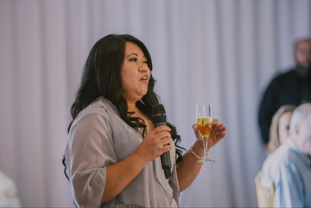 Woman delivering a toast at wedding with champagne glass.