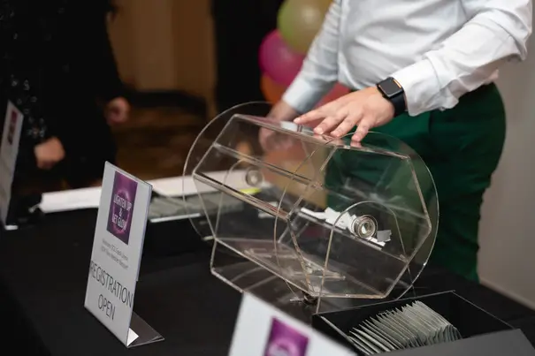 Clear rotating raffle drum with registration desk setup at event for prize drawing