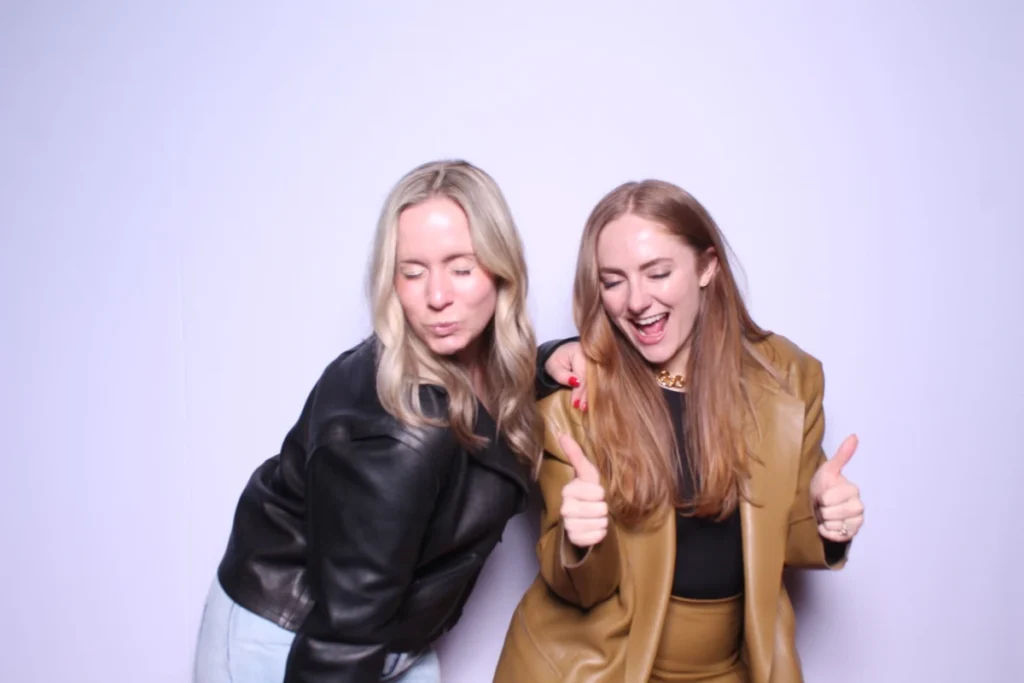 Fun photo booth poses with friends showing thumbs up and silly expressions, wearing trendy leather and tan outfits