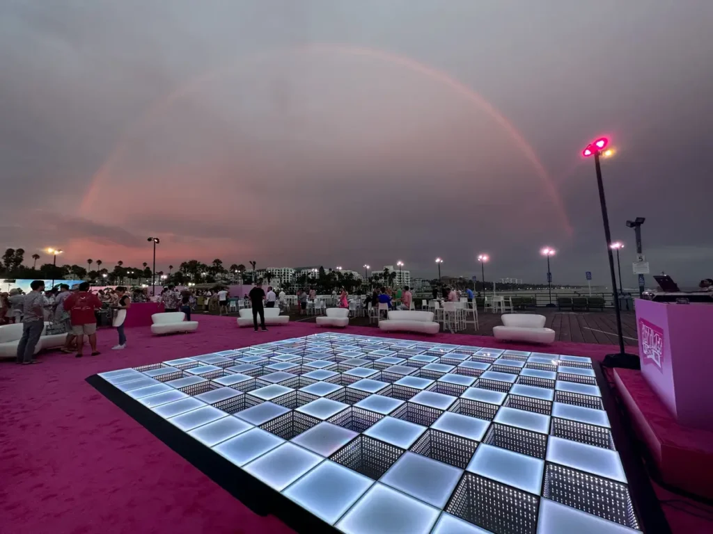 LED dance floor on pink carpet at outdoor venue, showing ideal sizing for medium gatherings with lounge seating and rainbow backdrop