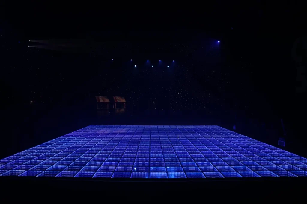 Large LED dance floor illuminated in bright blue, showcasing modern grid pattern design for corporate events