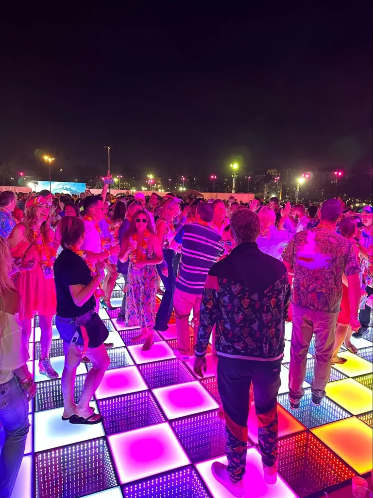 Packed LED dance floor with party guests demonstrating optimal space needed for large events with pink lighting