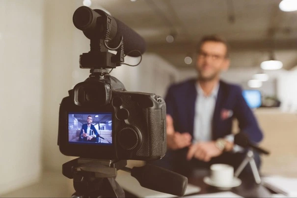 Professional camera recording a business person for a video confessional interview in an office setting