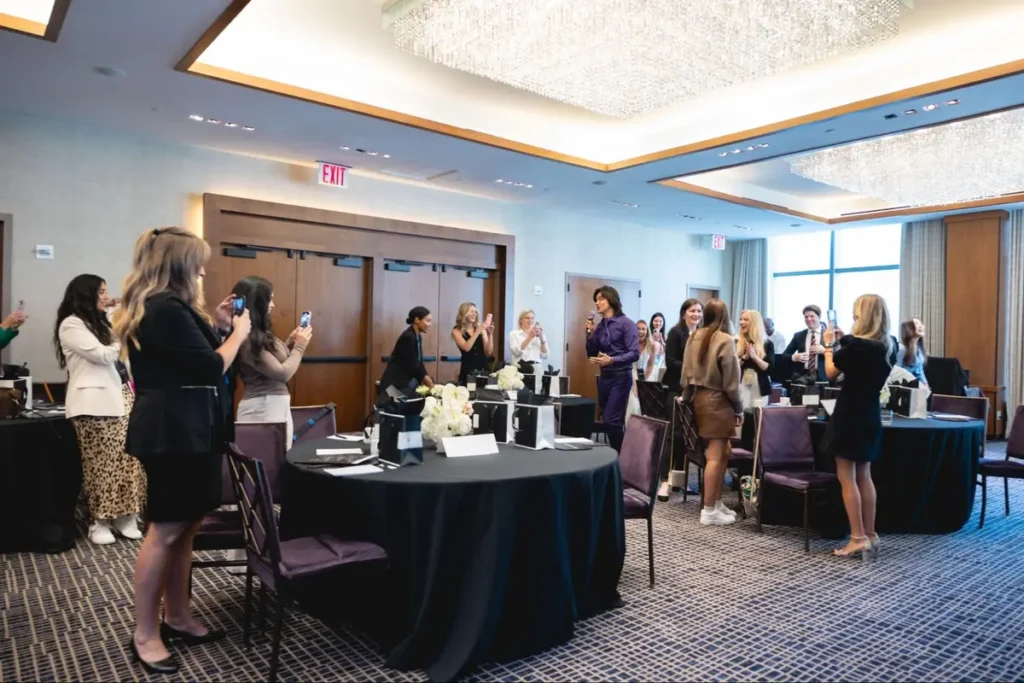 Corporate event in hotel conference room with attendees taking photos of speaker
