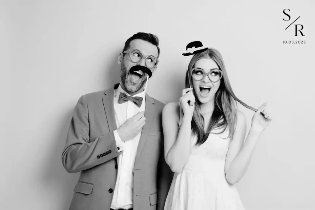 Couple posing with photo booth props including mustache and glasses at wedding, monogrammed with SR and date