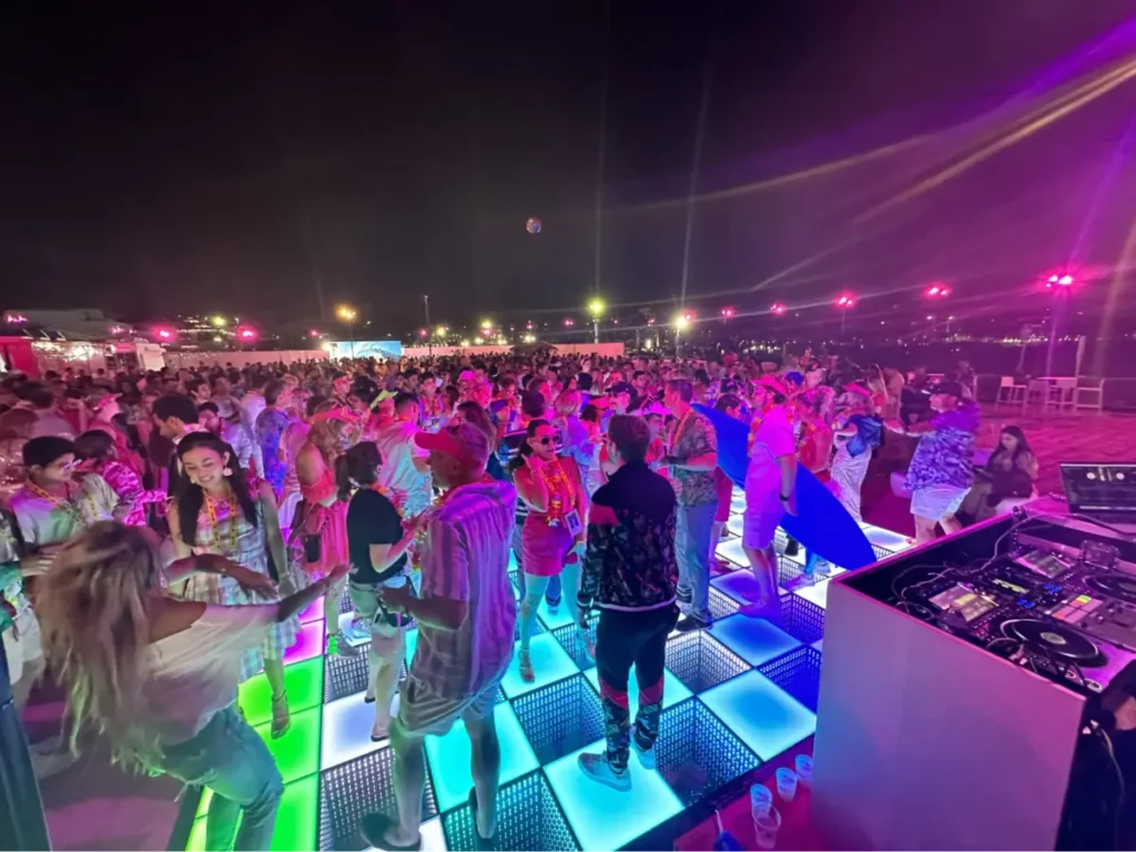 Crowded outdoor festival with colorful LED dance floor and DJ setup - popular floor styles require early booking