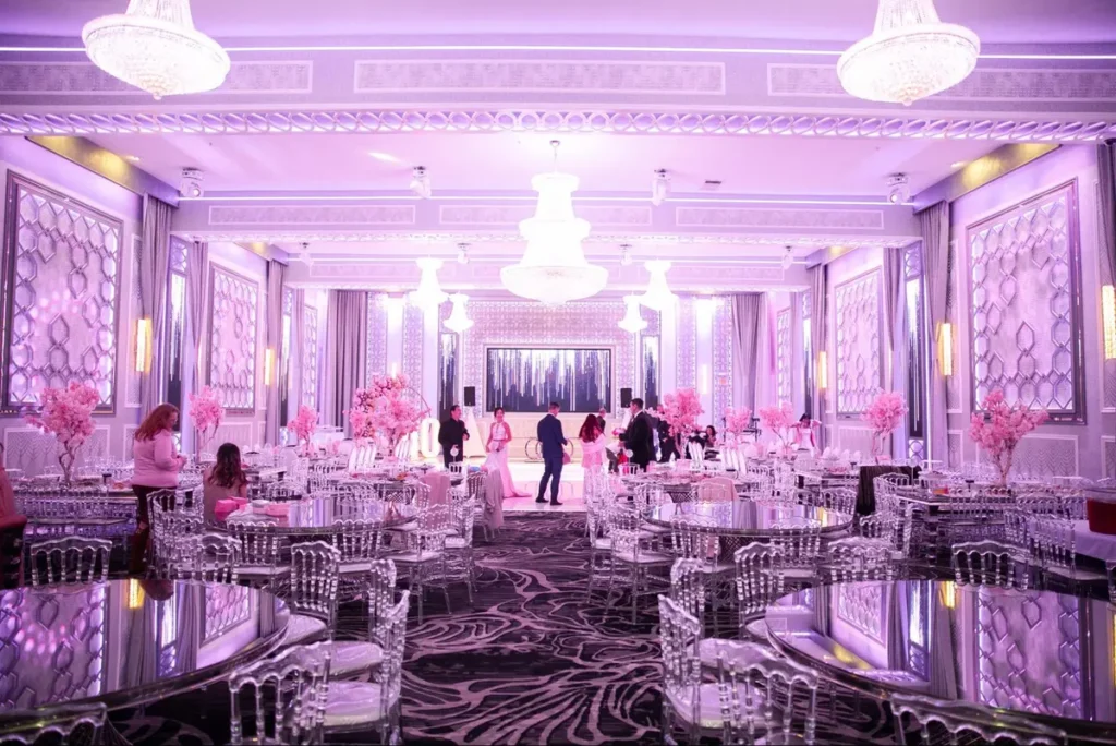 Elegant banquet hall with purple lighting, crystal chandeliers, and cherry blossom centerpieces creating a luxurious atmosphere