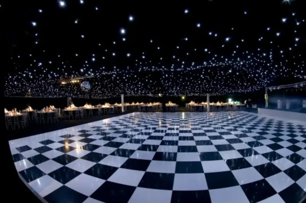 Elegant black and white checkered dance floor under a starry ceiling with banquet tables at a formal event venue