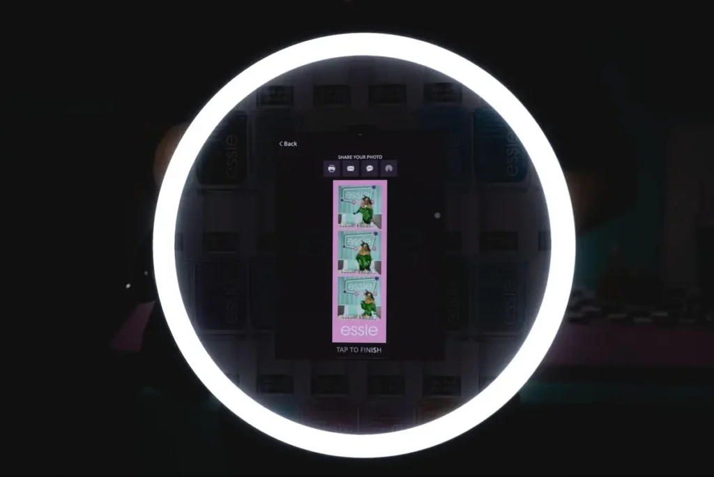 Essie branded photo booth sharing screen with ring light, custom photo strip template, and social sharing options for event guests